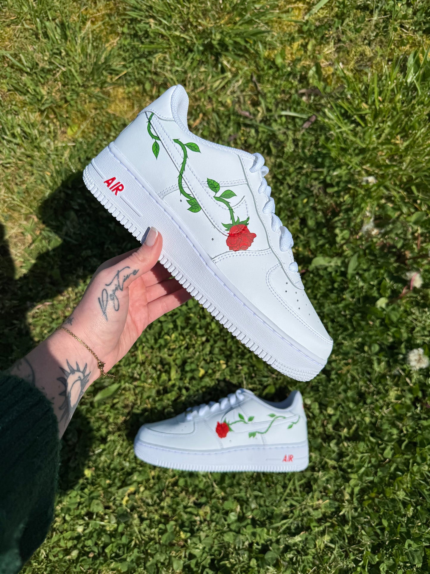 Sneakers Nike Air Force 1 personnalisées à la main avec une rose piquante dont la tige verte entoure le logo Nike.