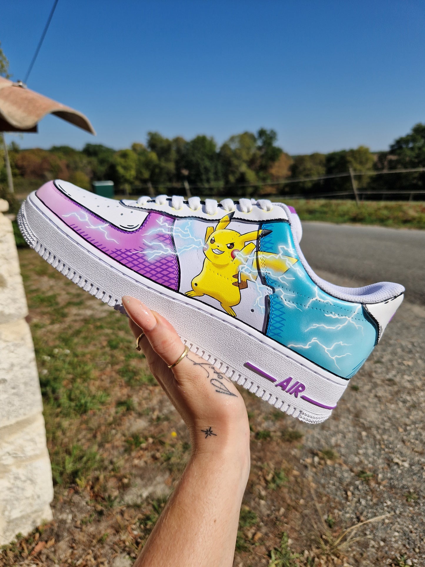 Imagen de las Nike Air Force 1 personalizadas Pikachu estilo cartoon. Cada zapatilla representa a Pikachu en una postura diferente, rodeado de rayos, sobre un fondo azul y violeta. Diseño personalizable y pintura resistente al agua. Un par perfecto para los fans de Pokémon y del custom streetwear.