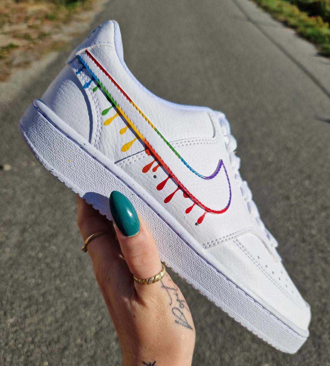 Zapatilla izquierda de Nike Air Force 1 personalizada con detalles de pintura multicolor sobre el logo Nike, diseño vibrante y moderno.