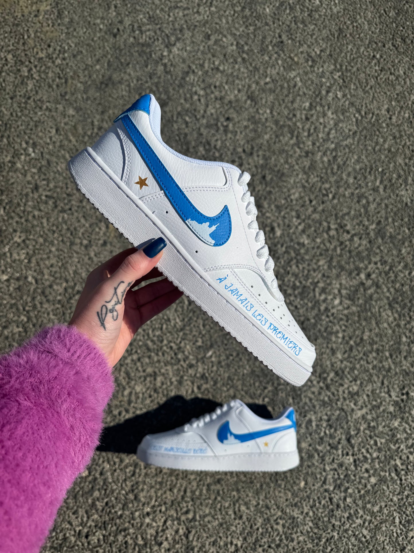 Nike court vision low custom OM avec swoosh bleus et silhouette de la Bonne Mère, logo OM à l’avant, étoile dorée à l’arrière et swoosh internes en dégradé bleu et blanc.