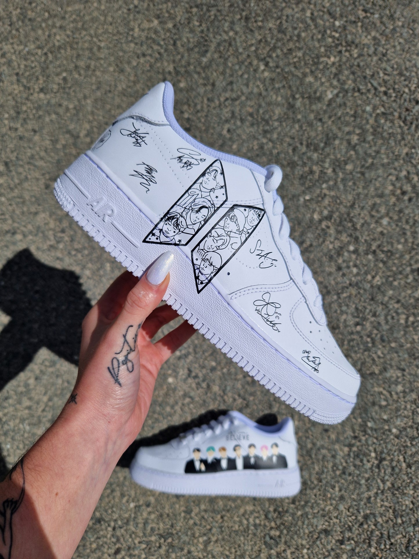 Zapatilla Nike Air Force 1 blanca personalizada a mano con las firmas de los miembros de BTS, diseño artístico y detallado sobre cuero blanco.