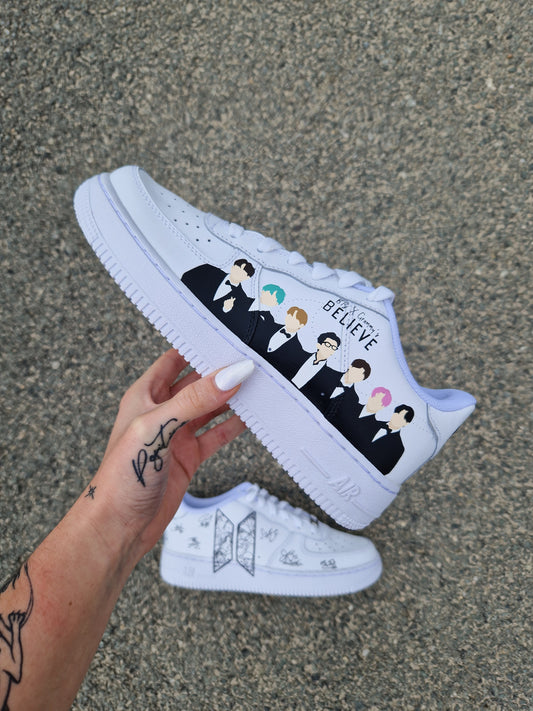 Zapatilla Nike Air Force 1 blanca con un retrato minimalista del grupo BTS pintado a mano, estilo moderno y elegante.