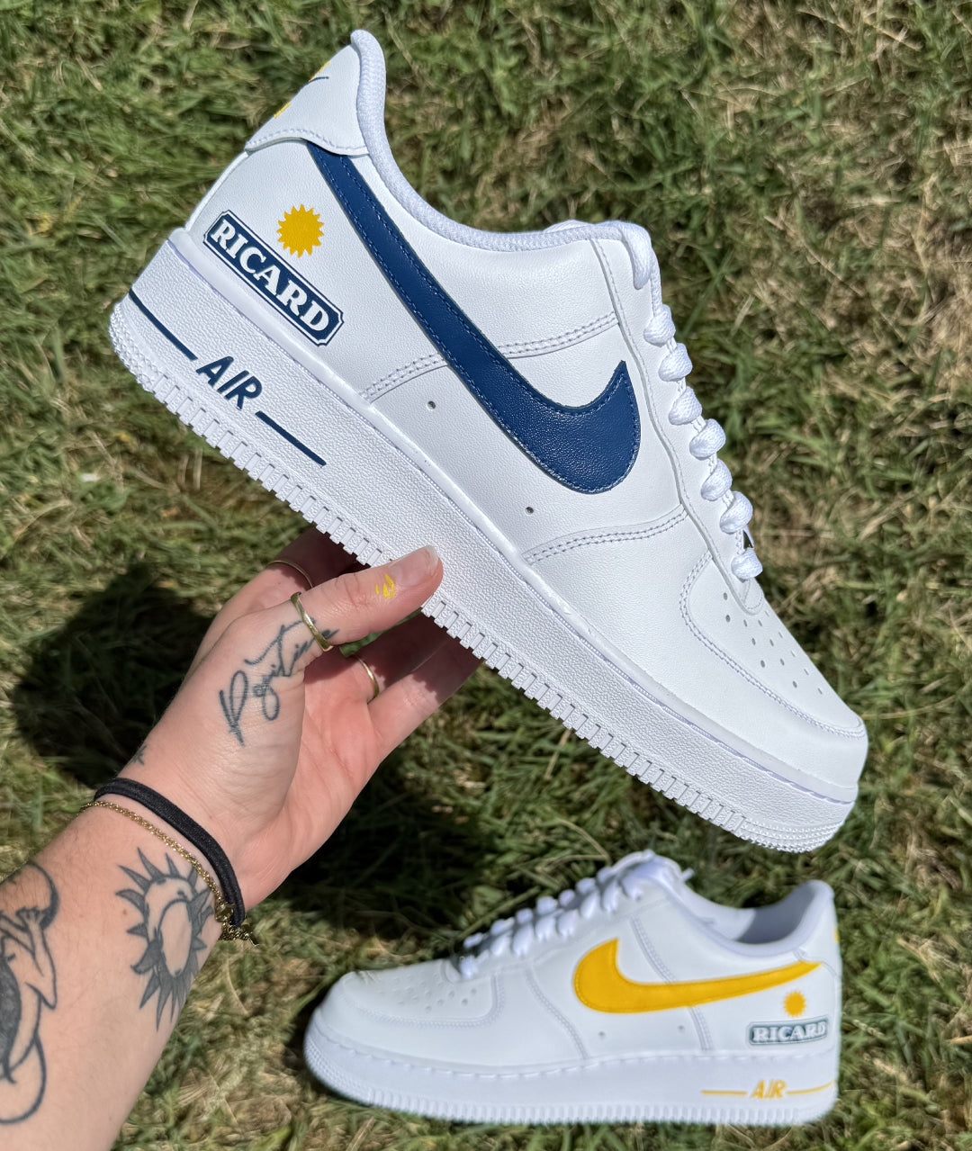 Zapatilla derecha de Nike Air Force 1 custom con los logos Nike en azul y amarillo y el logo Ricard pintado en el talón.