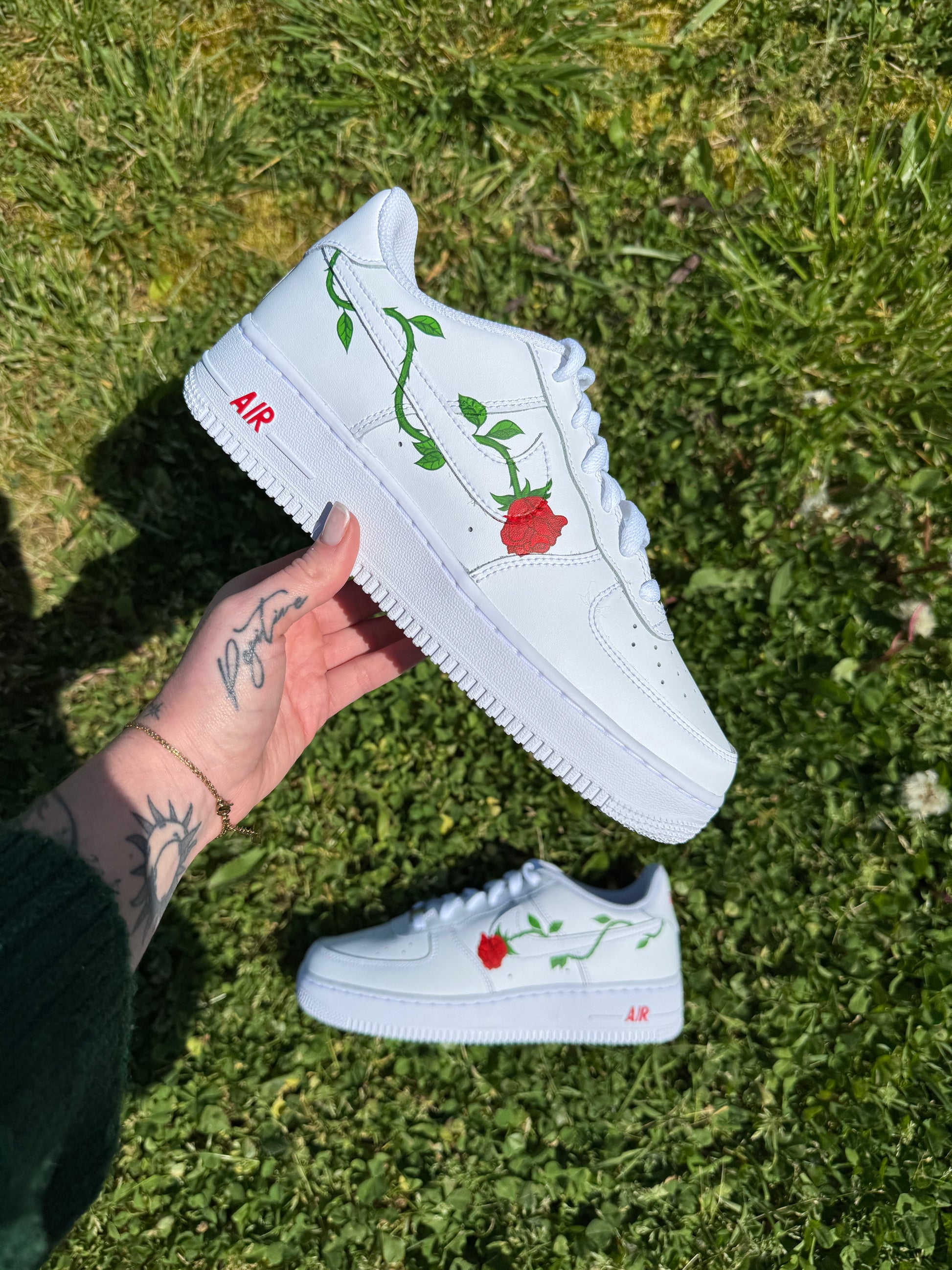 Sneakers Nike Air Force 1 personnalisées à la main avec une rose piquante dont la tige verte entoure le logo Nike.