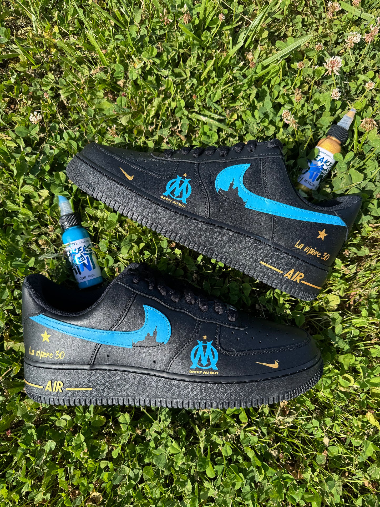 Nike Air Force 1 noire custom OM avec swoosh bleus et silhouette de la Bonne Mère, logo OM à l’avant, étoile dorée à l’arrière et swoosh internes en dégradé bleu et noir.