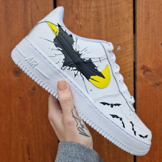 Nike Air Force 1 custom Batman avec swoosh jaunes, logo chauve-souris noir et chauves-souris en vol peintes à la main.