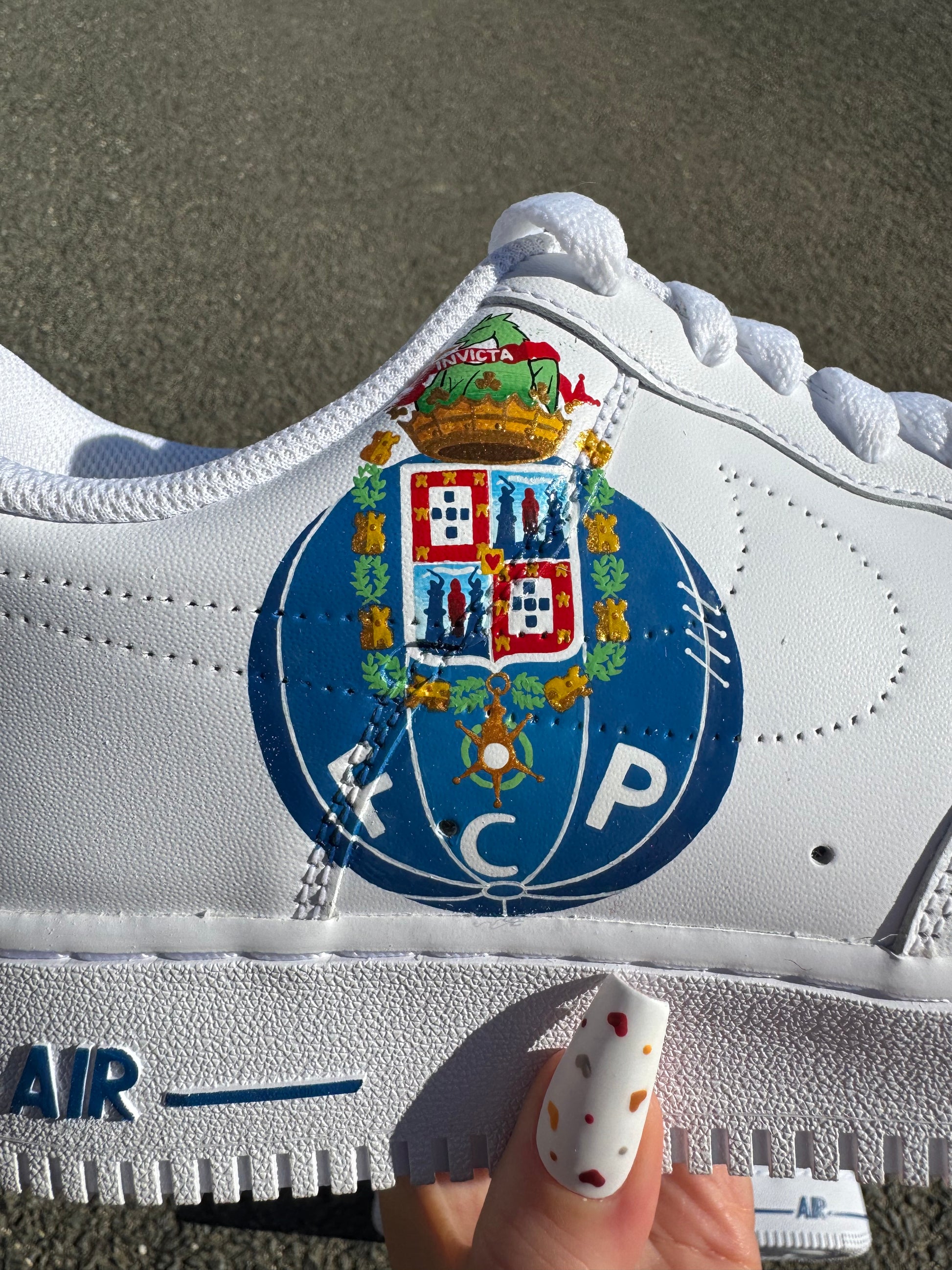 Nike Air Force 1 custom avec logo FC Porto peint à la main sur une chaussure, swoosh dégradé bleu et inscription “FC PORTO” sur l’autre. Vue sur les détails du logo au centre.