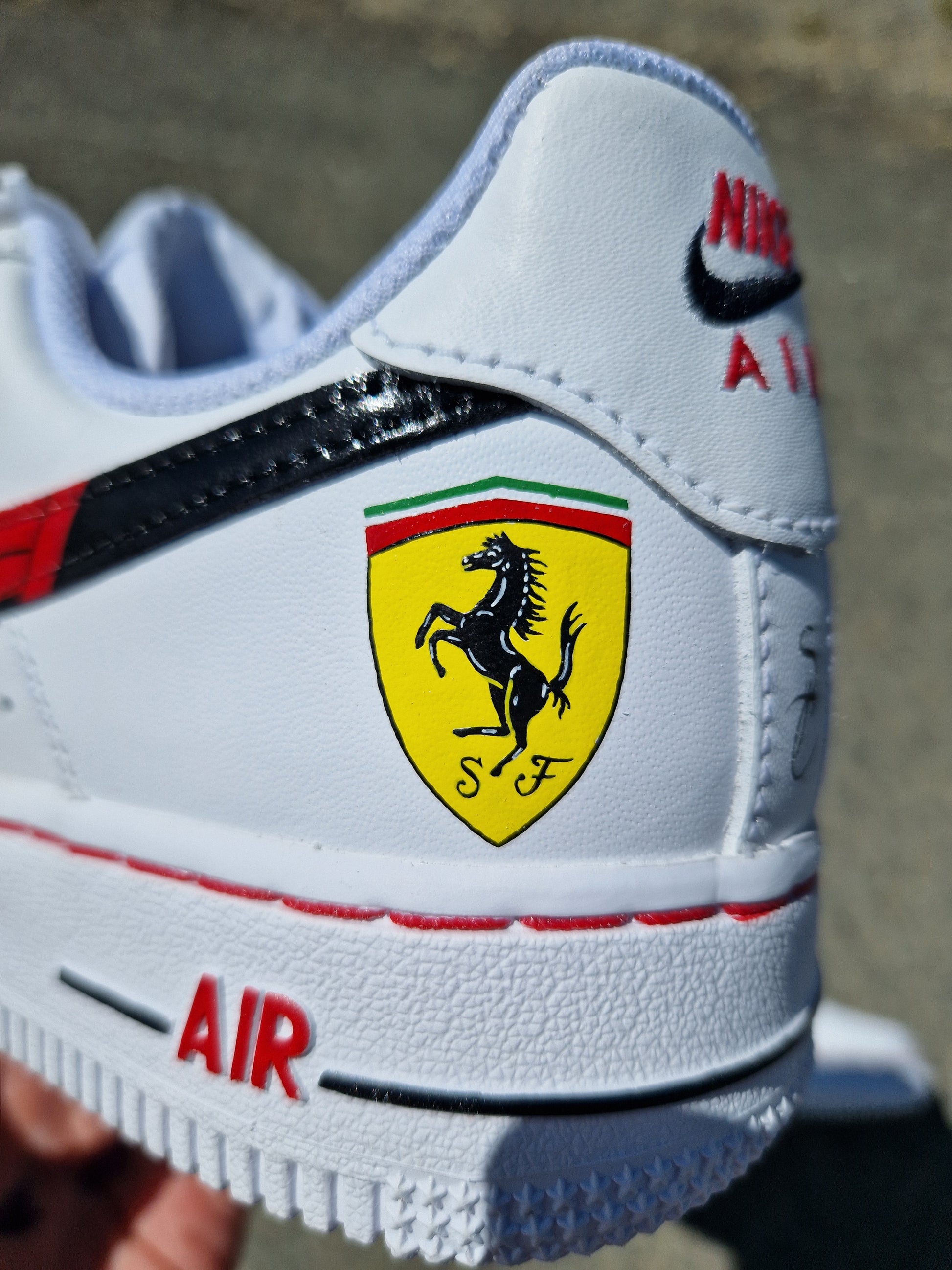 Foto de las Nike Air Force 1 personalizadas de Ferrari con 4 swoosh negros, logo F1 y diferentes logos de Ferrari en los laterales externos. Pintura a mano, acabado resistente.