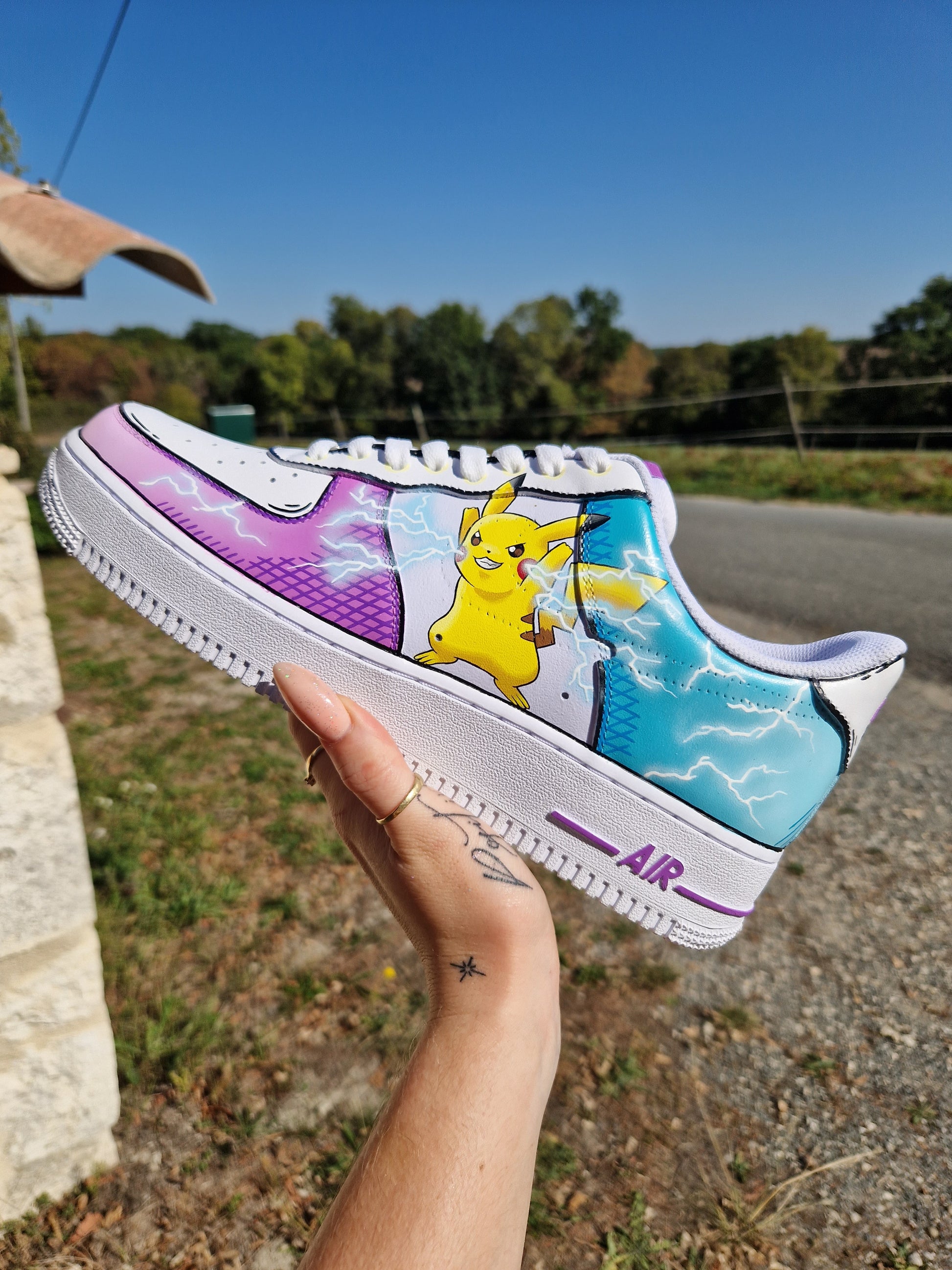 Imagen de las Nike Air Force 1 personalizadas Pikachu estilo cartoon. Cada zapatilla representa a Pikachu en una postura diferente, rodeado de rayos, sobre un fondo azul y violeta. Diseño personalizable y pintura resistente al agua. Un par perfecto para los fans de Pokémon y del custom streetwear.