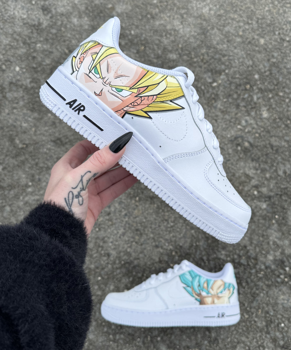 Modelo mostrado: Nike Air Force 1 personalizadas de DBZ con Son Goku en Super Saiyan Blue en un zapato y Son Goku en Super Saiyan clásico en el otro. Pintura a mano con detalles cuidadosos, resistente al agua. Personaliza tu par eligiendo tus dos personajes favoritos de Dragon Ball Z.