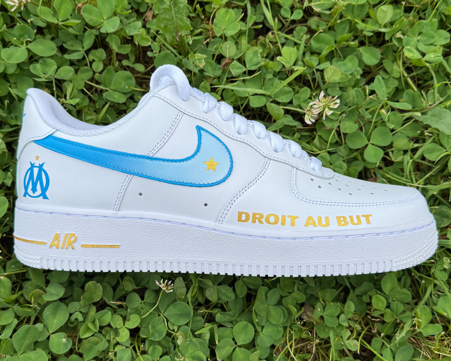 Nike Air Force 1 Custom OM – Droit au but : swoosh bleu et blanc, logo OM, étoile dorée et devise en doré. Une création 100% marseillaise.
