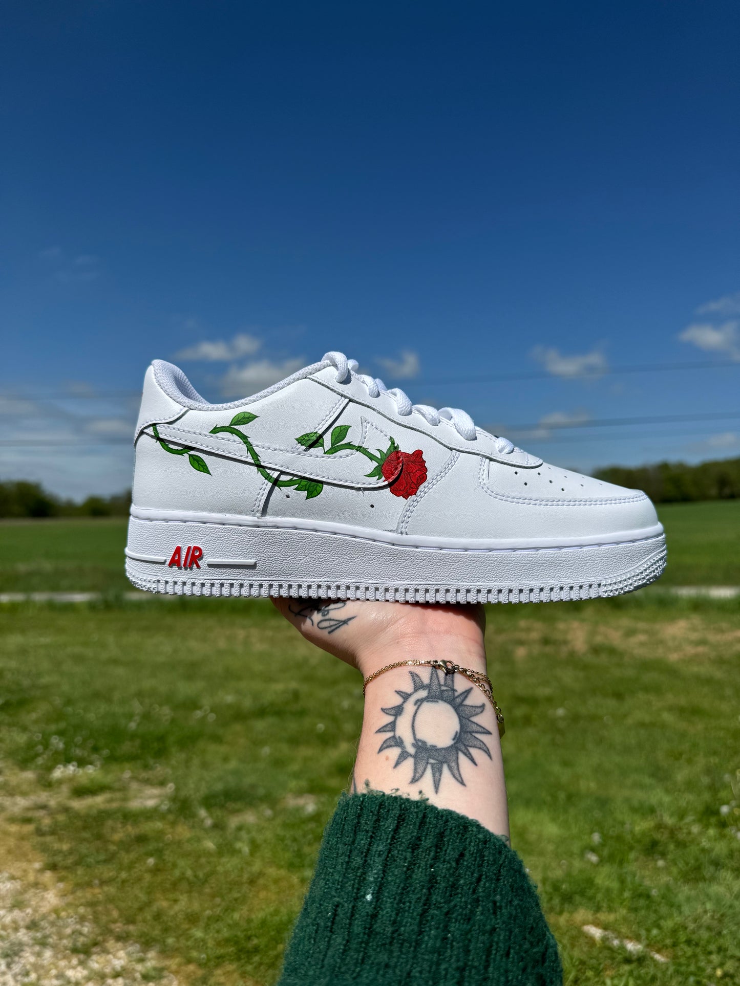 Sneakers Nike Air Force 1 personnalisées avec une rose piquante dont la tige entoure le logo Nike.