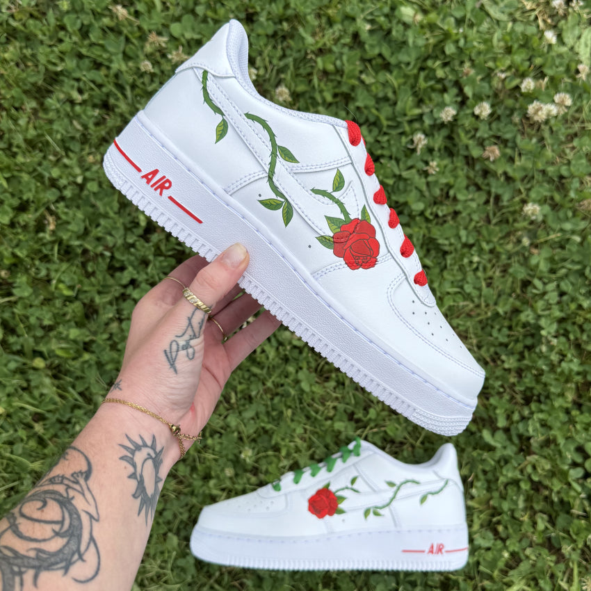Sneakers Nike Air Force 1 personnalisées avec une rose piquante dont la tige entoure le logo Nike.