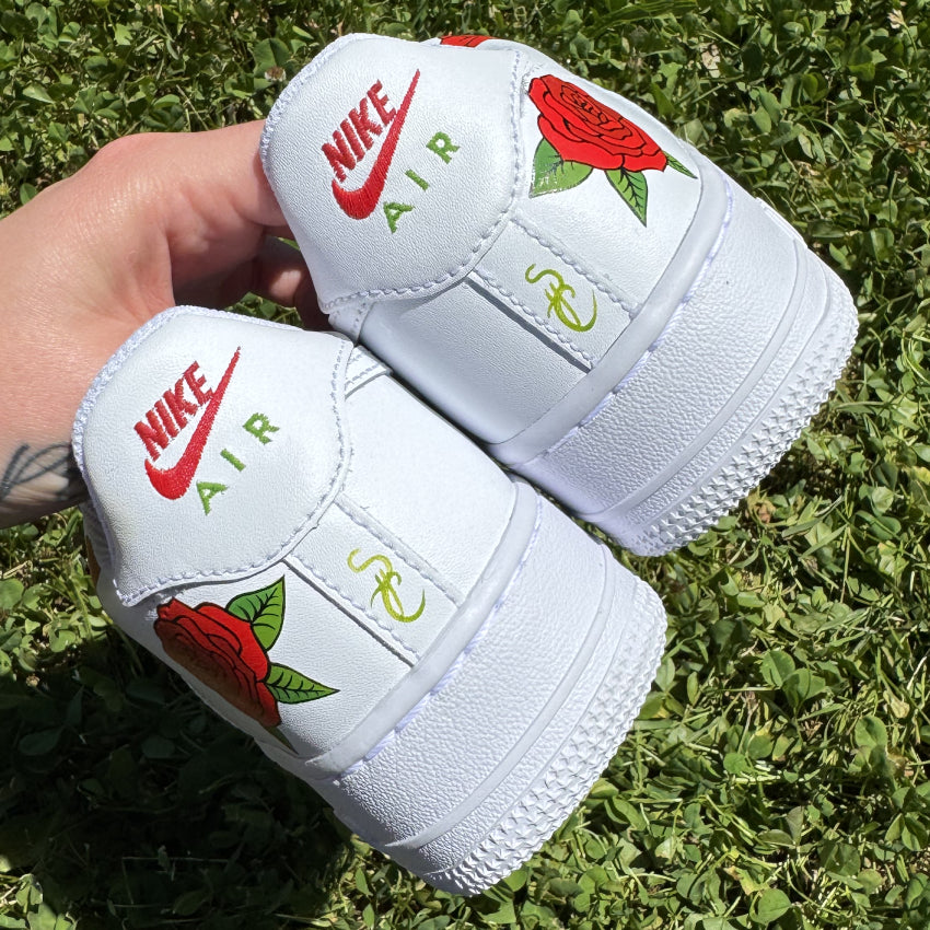 Vue arrière des Nike Air Force 1 customisées avec trois roses rouges sur les côtés et la signature de l’artiste sur l'arrière.