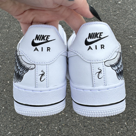 Nike Air Force 1 custom avec aile d’ange peinte à la main sur les côtés externes – design artistique et symbolique. Vu de l'arrière avec la signature de l'artiste
