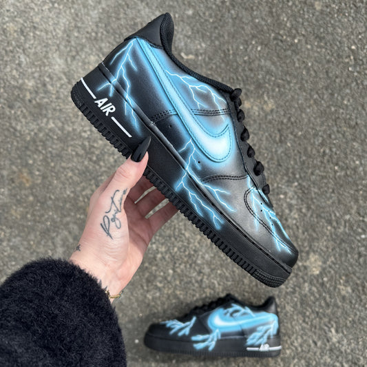 Nike Air Force 1 noire customisée avec éclairs bleus peints à la main sur les côtés internes et externes.