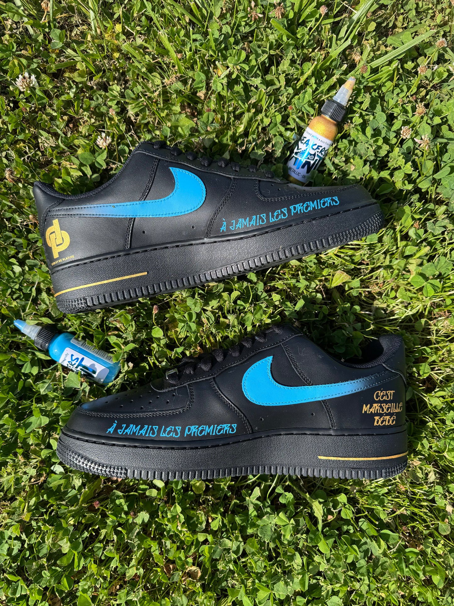 Nike Air Force 1 noir custom OM côté interne avec swoosh dégradé bleus et noir. Phrase "c'est Marseille bébé" en doré et "A jamais les premiers" 