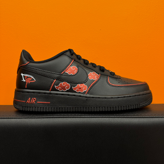 Nike Air Force 1 personalizadas Akatsuki con nubes rojas sobre fondo negro, contornos rojos y el Sharingan de Itachi pintado en la parte trasera.