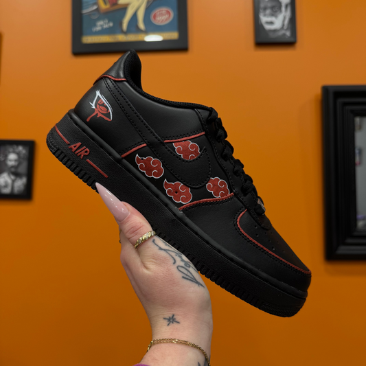 Nike Air Force 1 negras personalizadas Akatsuki con nubes rojas sobre fondo negro, contornos rojos y el Sharingan de Itachi pintado en la parte trasera.
